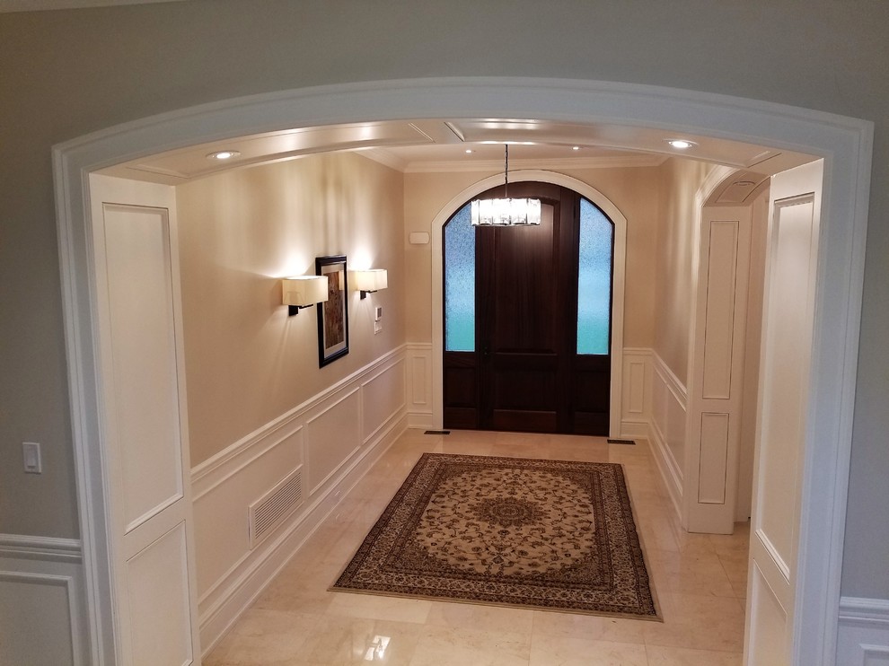 Idées déco pour un grand hall d'entrée classique avec un mur beige, un sol en carrelage de céramique, une porte simple, une porte en bois foncé et un sol beige.