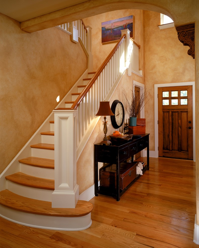 На фото: прихожая: освещение в классическом стиле с оранжевыми стенами, одностворчатой входной дверью и входной дверью из дерева среднего тона с