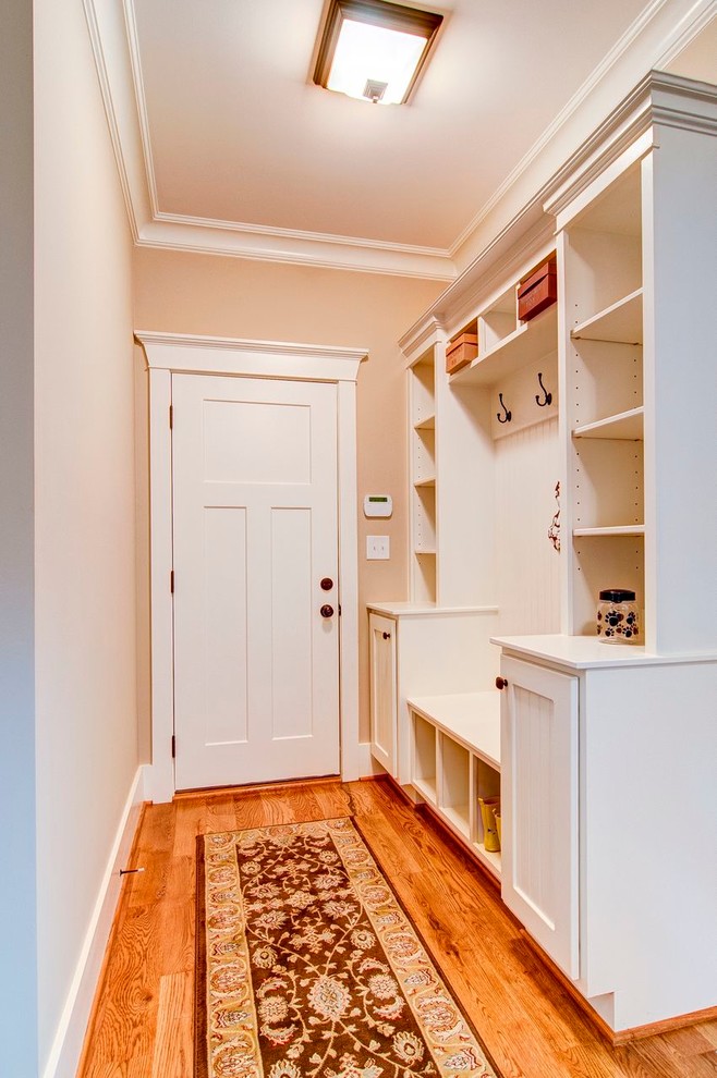 Foto de distribuidor clásico de tamaño medio con paredes beige, suelo de madera en tonos medios y puerta blanca