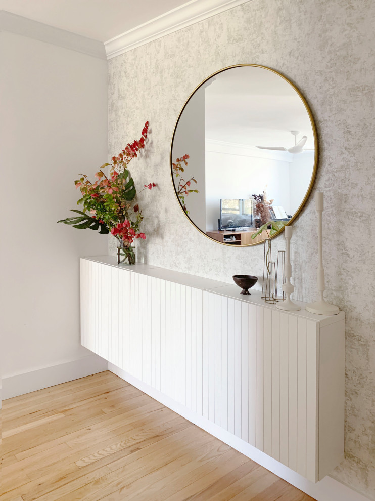 This is an example of a small scandi foyer in New York with metallic walls, light hardwood flooring and beige floors.