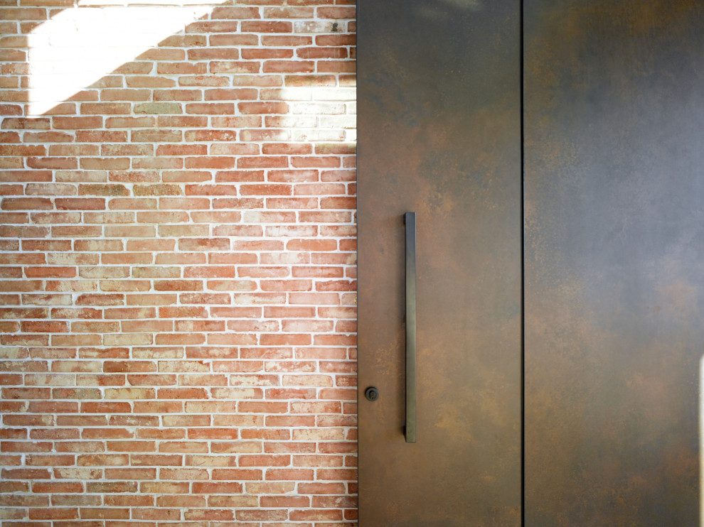 Ejemplo de distribuidor abovedado industrial de tamaño medio con paredes blancas, suelo de granito, puerta pivotante, puerta metalizada, suelo negro y ladrillo