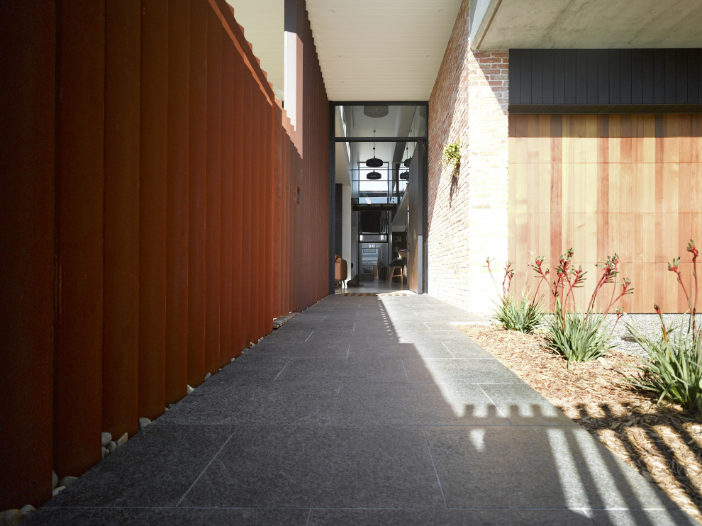 Idee per un ingresso industriale di medie dimensioni con pareti bianche, pavimento in granito, una porta a pivot, una porta in metallo, pavimento nero, soffitto a volta e pareti in mattoni