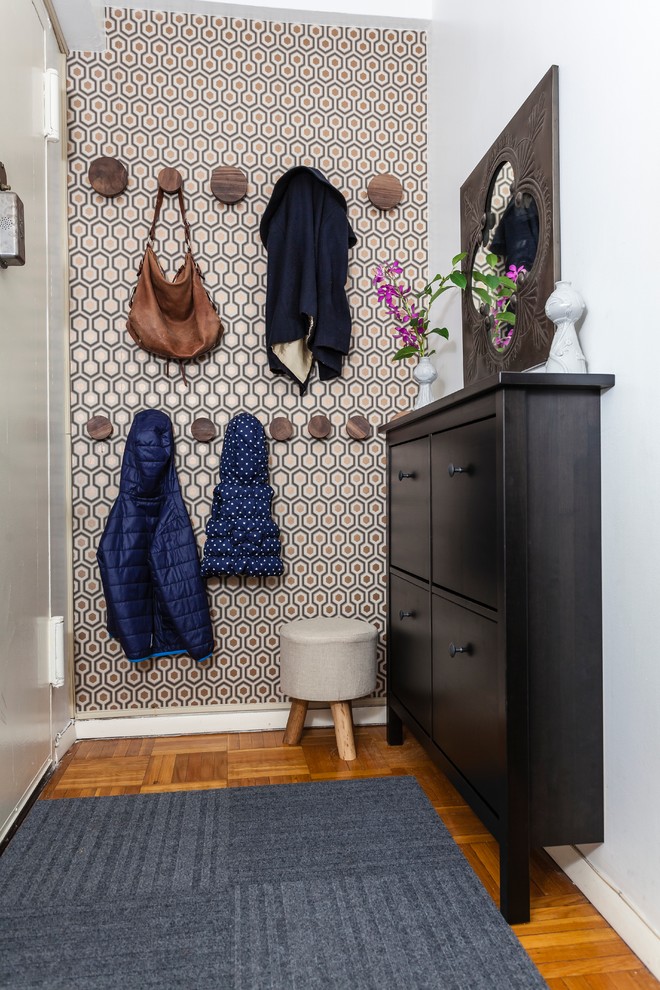 Inspiration for a small transitional medium tone wood floor entryway remodel in New York with a white front door and metallic walls
