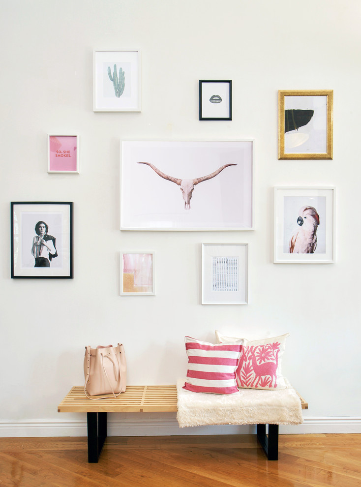 This is an example of an eclectic entrance in New York with white walls and medium hardwood flooring.