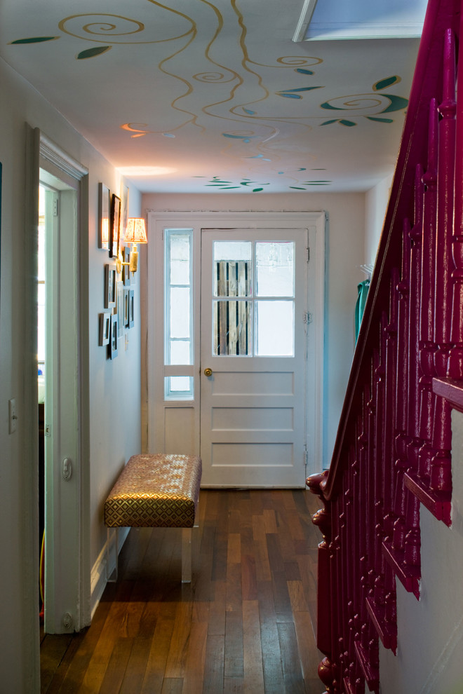 Eklektisk inredning av en entré, med vita väggar och en vit dörr