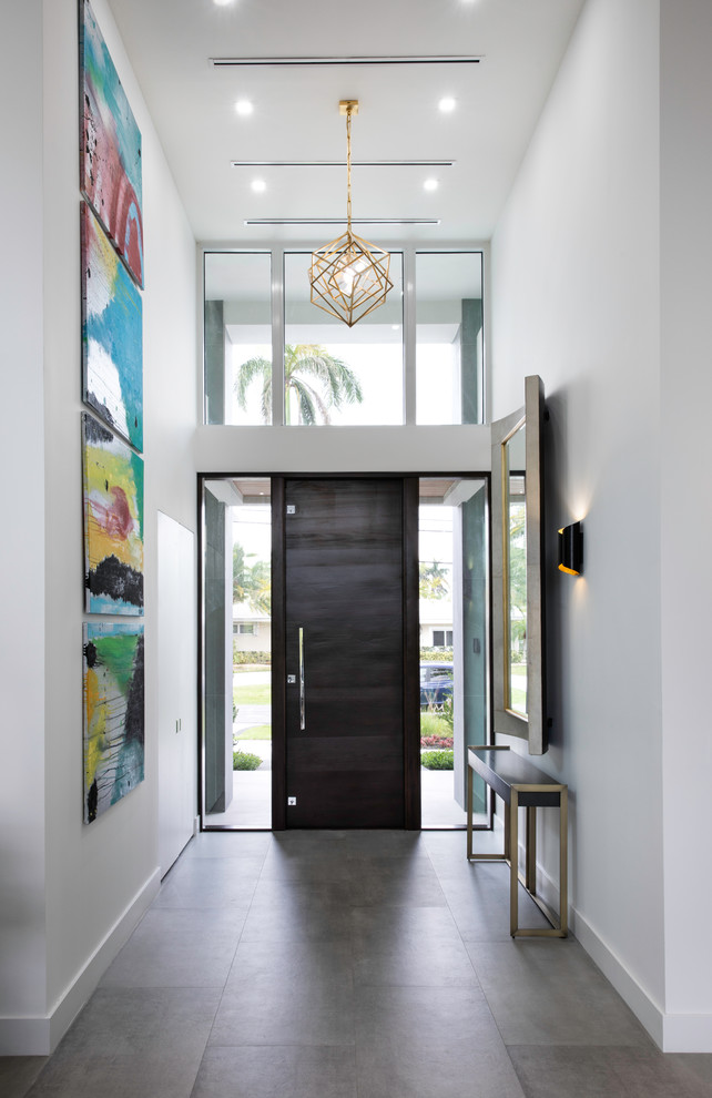 Réalisation d'un hall d'entrée design avec un mur blanc, une porte simple, une porte en bois foncé et un sol gris.