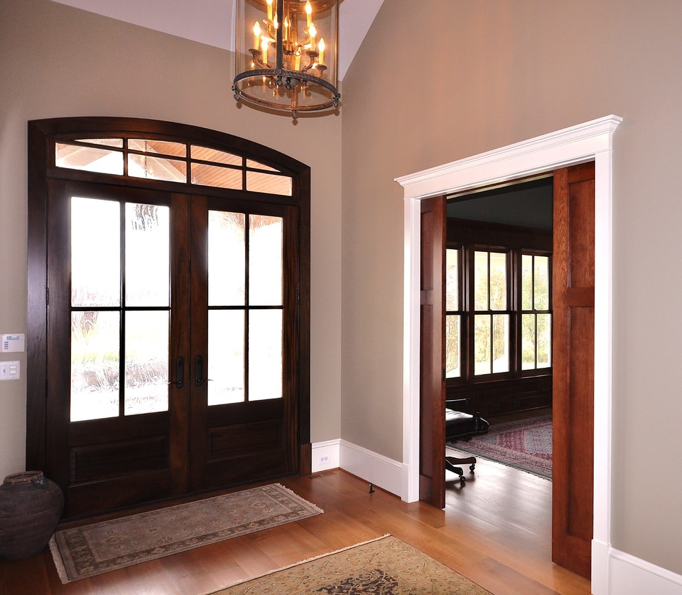 Cette image montre une porte d'entrée traditionnelle de taille moyenne avec un mur gris, une porte double, une porte en bois foncé, parquet clair et un sol beige.