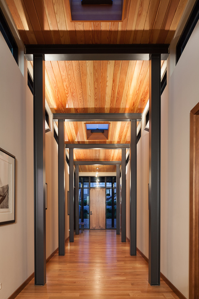 Imagen de hall contemporáneo de tamaño medio con paredes beige, suelo de madera clara, puerta simple, puerta de madera clara y suelo marrón