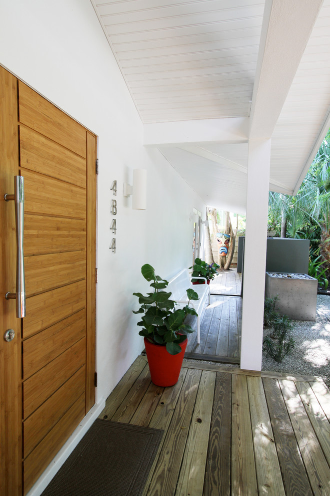 Cette image montre une porte d'entrée vintage de taille moyenne avec un mur blanc, une porte simple et un sol marron.