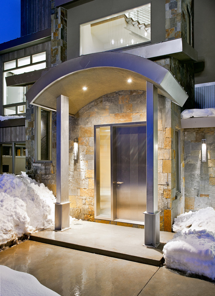 На фото: входная дверь среднего размера в современном стиле с одностворчатой входной дверью, металлической входной дверью, разноцветными стенами, бетонным полом и серым полом с