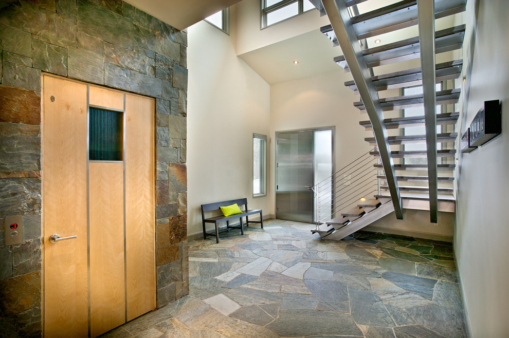 アトランタにあるラグジュアリーな広いコンテンポラリースタイルのおしゃれな玄関ロビー (金属製ドア、グレーの壁、グレーの床、スレートの床) の写真