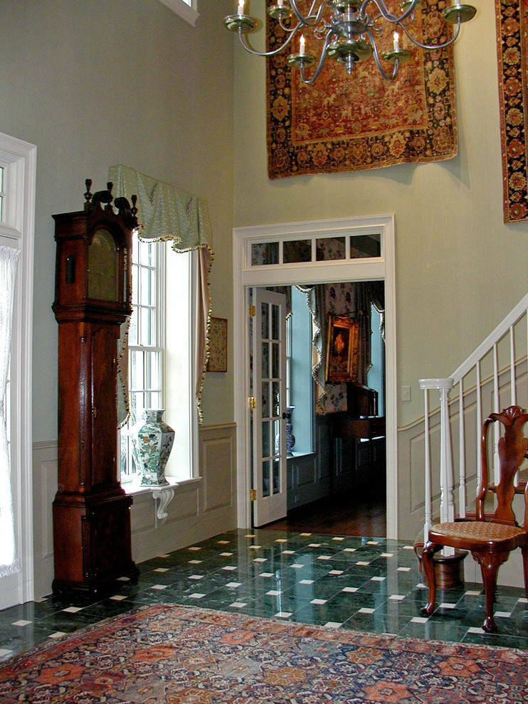 Aménagement d'un grand hall d'entrée classique avec une porte en bois brun, un mur jaune, un sol en marbre, une porte simple et un sol vert.