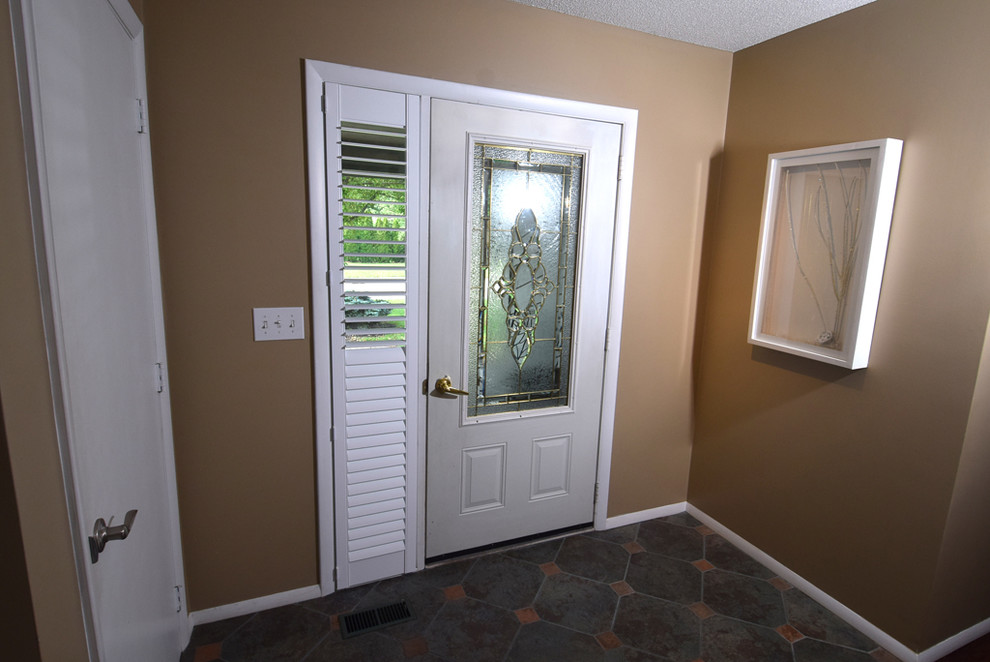 Cette image montre une porte d'entrée traditionnelle de taille moyenne avec un mur marron, un sol en carrelage de céramique, une porte simple, une porte blanche et un sol gris.