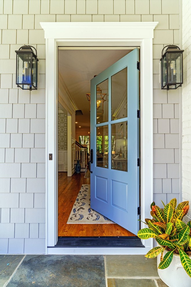 Bild på en stor ingång och ytterdörr, med grå väggar, kalkstensgolv, en enkeldörr, en blå dörr och flerfärgat golv