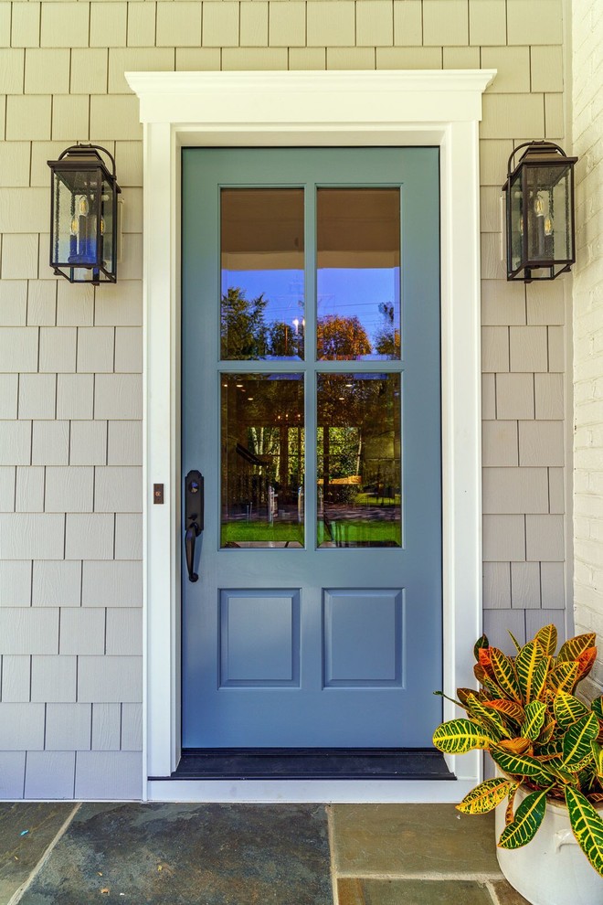Inredning av en stor ingång och ytterdörr, med grå väggar, kalkstensgolv, en enkeldörr, en blå dörr och flerfärgat golv