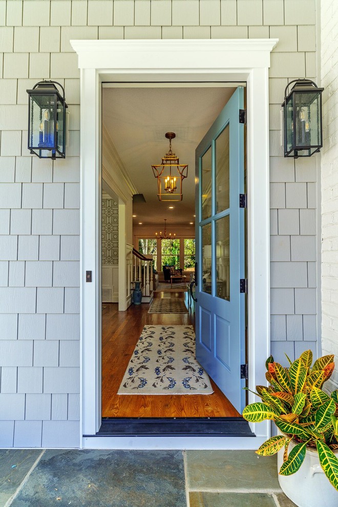 Réalisation d'une grande porte d'entrée avec un mur gris, un sol en calcaire, une porte simple, une porte bleue et un sol multicolore.