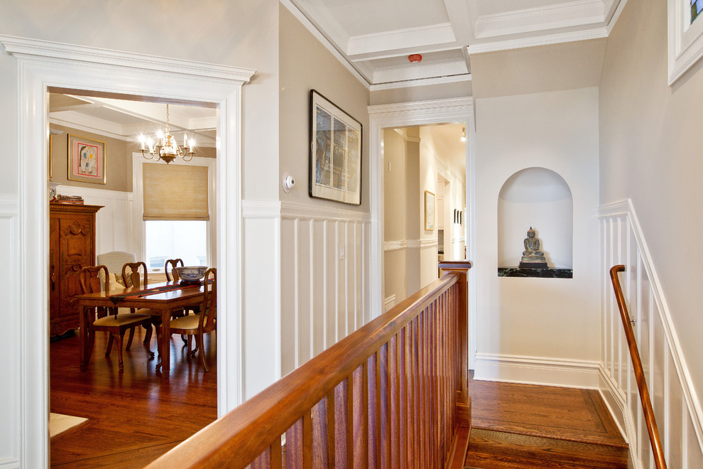 Idée de décoration pour une entrée tradition de taille moyenne avec un mur beige, un sol en bois brun, un couloir, une porte en bois brun et un sol marron.