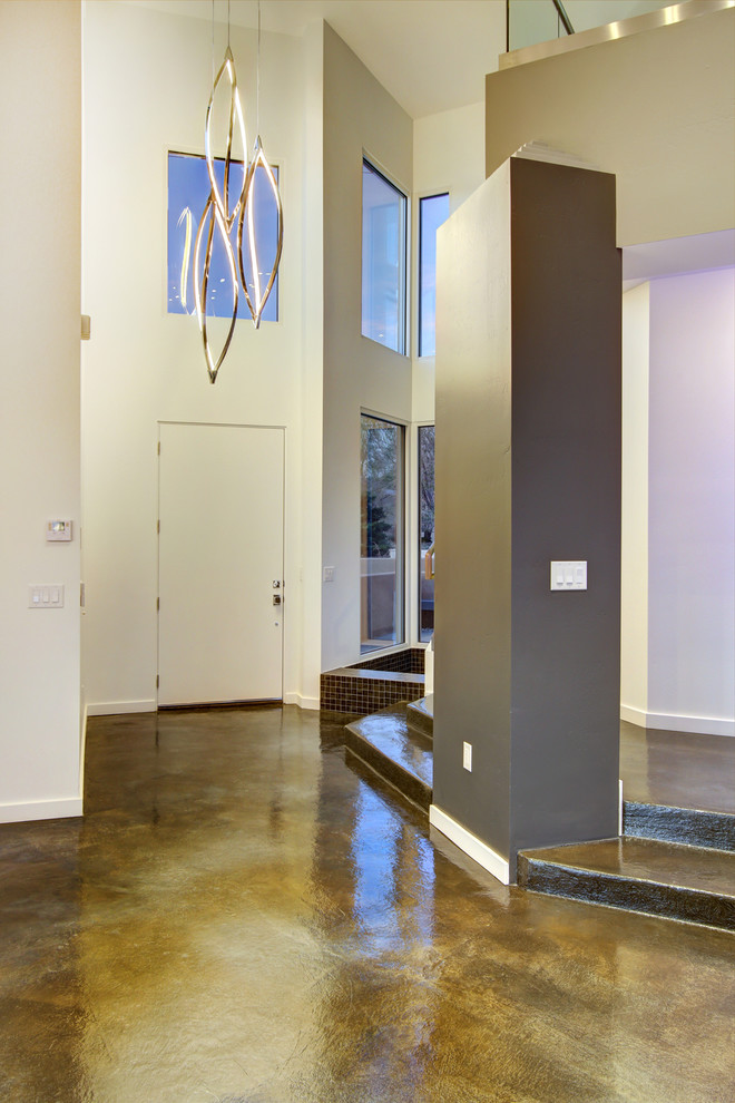 На фото: фойе среднего размера в современном стиле с белыми стенами, бетонным полом, одностворчатой входной дверью и белой входной дверью с