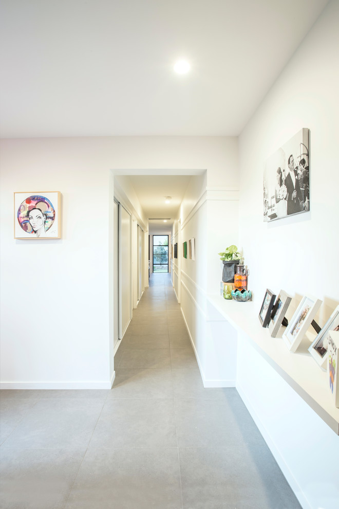 Exemple d'une petite entrée tendance avec un couloir, un mur blanc, un sol en carrelage de porcelaine, une porte simple, une porte rouge et un sol gris.
