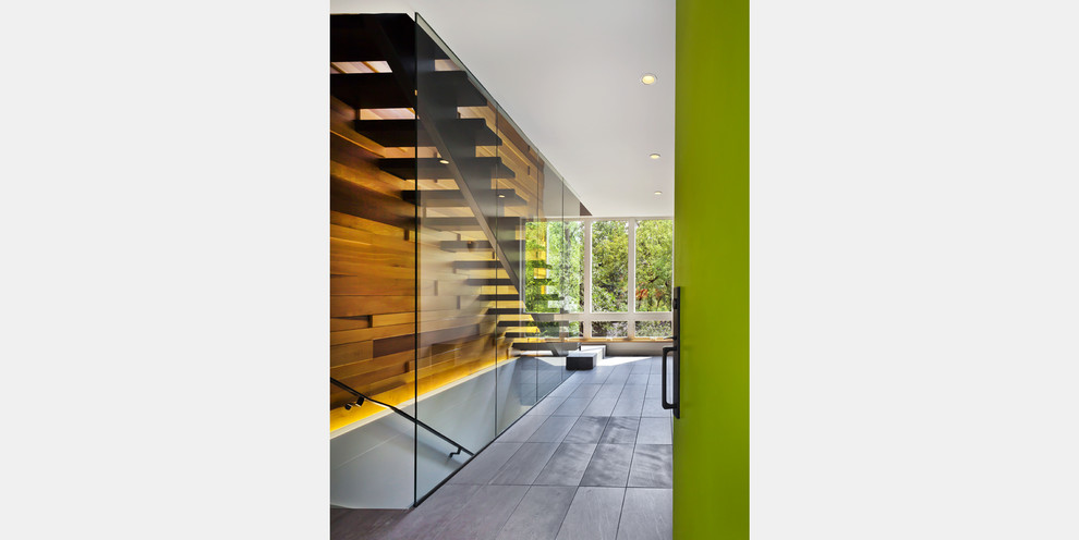 Immagine di un corridoio minimal di medie dimensioni con pareti bianche, pavimento in gres porcellanato, una porta singola e una porta verde