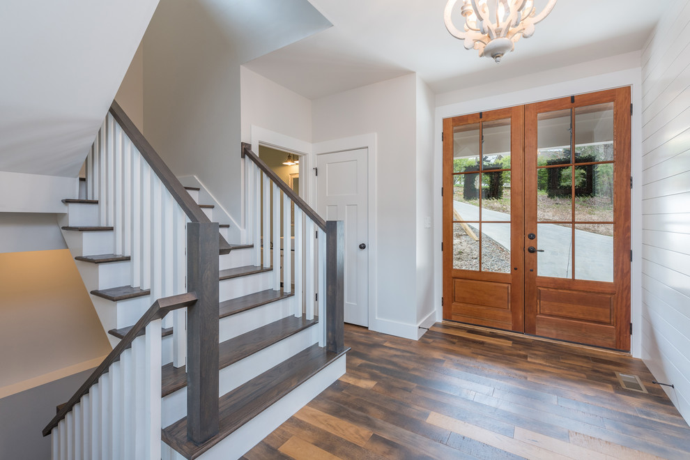 Idée de décoration pour une porte d'entrée tradition de taille moyenne avec un mur gris, un sol en bois brun, une porte double, une porte en bois clair et un sol marron.