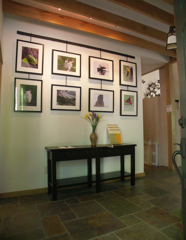 На фото: фойе среднего размера в современном стиле с одностворчатой входной дверью, белыми стенами, полом из сланца и разноцветным полом