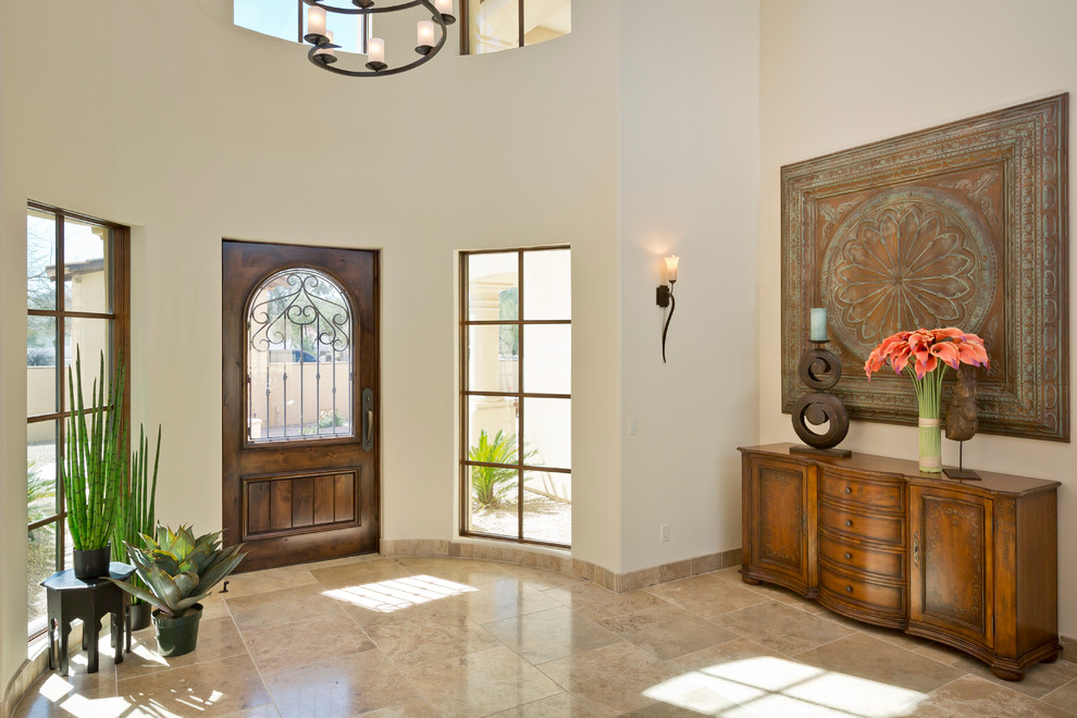 フェニックスにあるラグジュアリーな広いトラディショナルスタイルのおしゃれな玄関ロビー (ベージュの壁、トラバーチンの床、茶色いドア) の写真