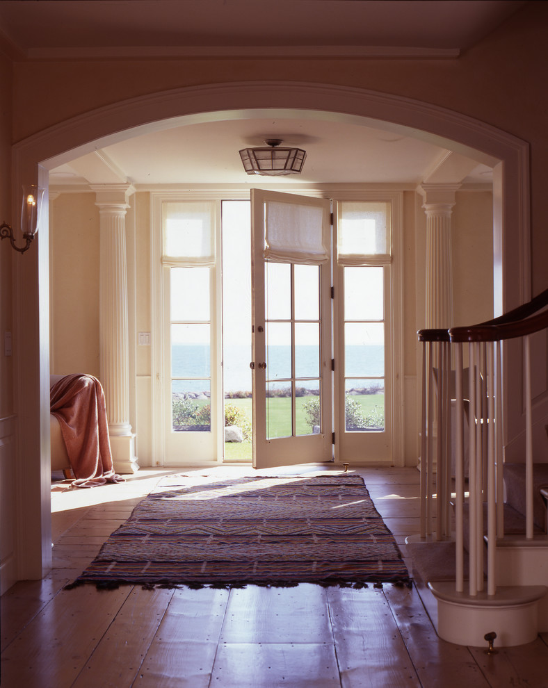 Modelo de distribuidor costero de tamaño medio con paredes beige, suelo de madera clara, puerta simple y puerta de vidrio