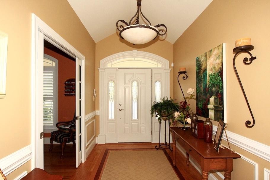 Стильный дизайн: фойе среднего размера в классическом стиле с желтыми стенами, паркетным полом среднего тона, одностворчатой входной дверью и белой входной дверью - последний тренд