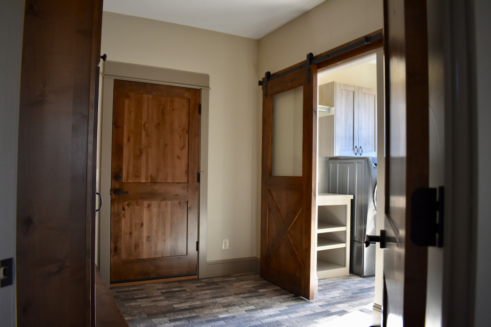 Imagen de vestíbulo posterior campestre de tamaño medio con paredes beige, suelo de ladrillo, puerta simple, puerta de madera en tonos medios, suelo multicolor y vigas vistas