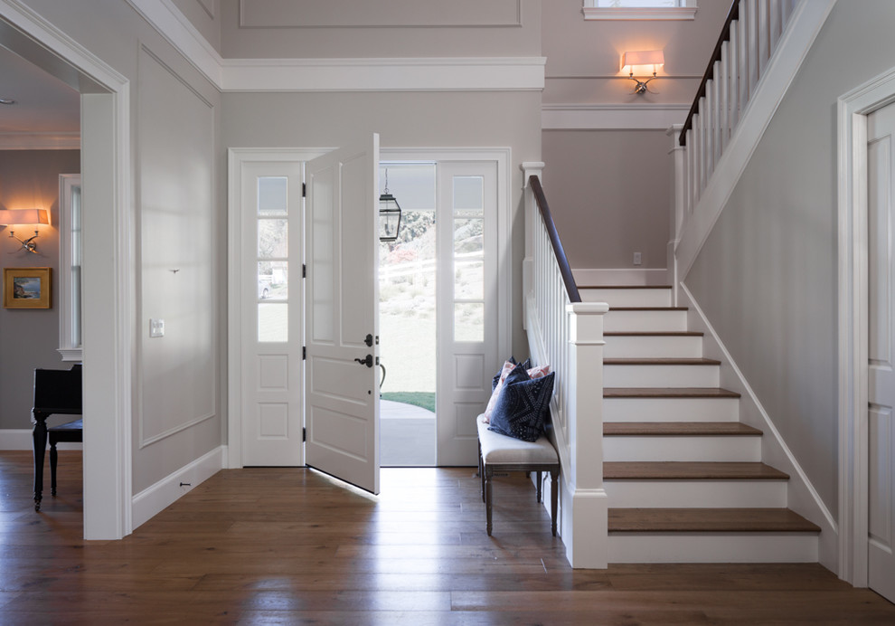 Réalisation d'un hall d'entrée tradition de taille moyenne avec un mur beige, un sol en bois brun, une porte simple et une porte blanche.