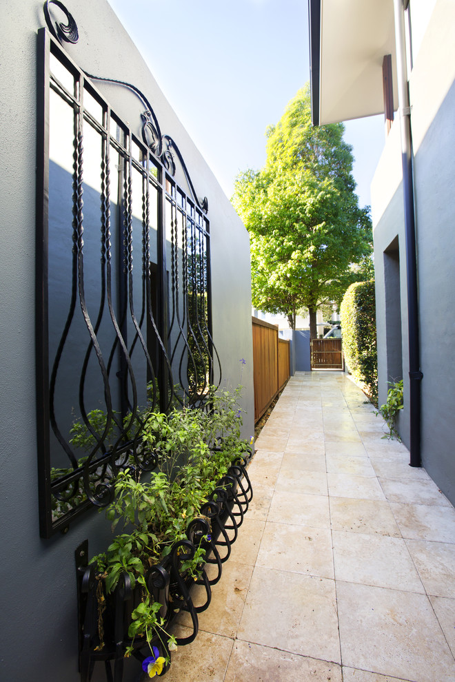 На фото: маленькая узкая прихожая в современном стиле с серыми стенами, полом из травертина, одностворчатой входной дверью, входной дверью из дерева среднего тона и бежевым полом для на участке и в саду с