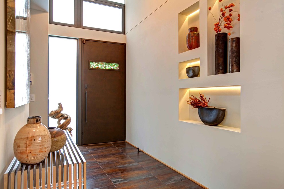 Ejemplo de entrada contemporánea con paredes beige, puerta simple, puerta de madera oscura y suelo marrón