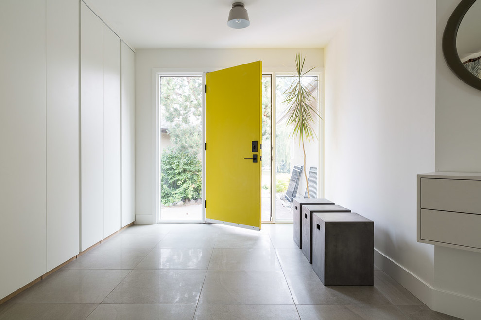 Foto di una porta d'ingresso minimal di medie dimensioni con pareti bianche, pavimento con piastrelle in ceramica, una porta singola, una porta gialla e pavimento marrone