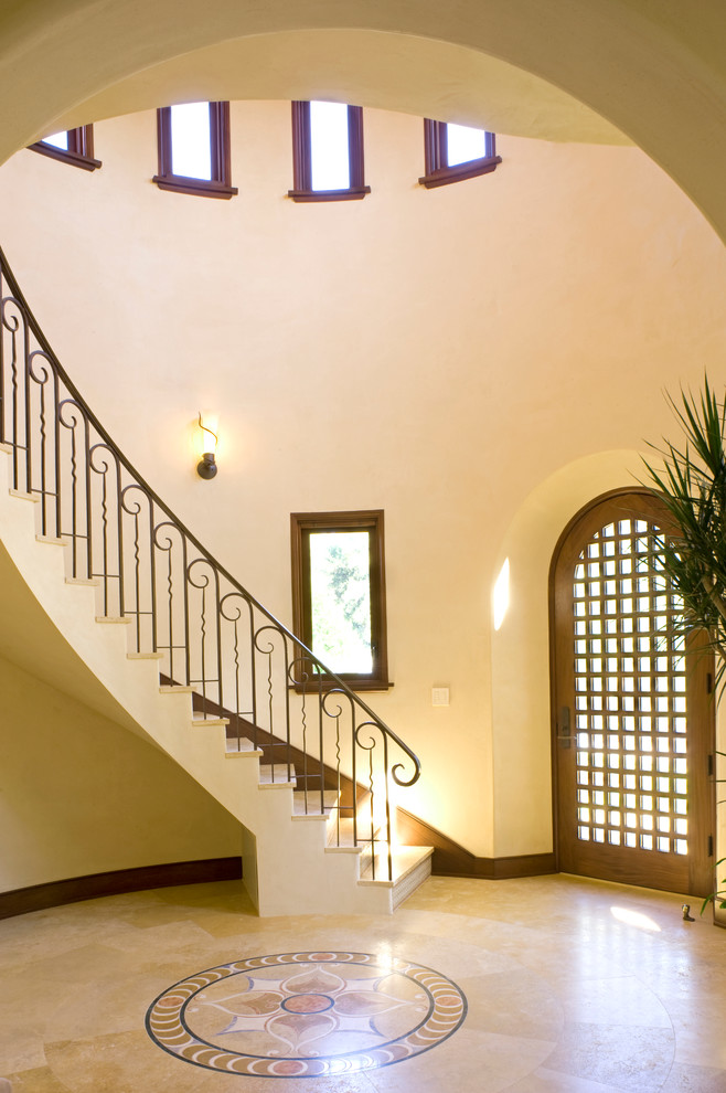 This is an example of a large mediterranean foyer in San Francisco with beige walls, limestone flooring, a single front door and a dark wood front door.