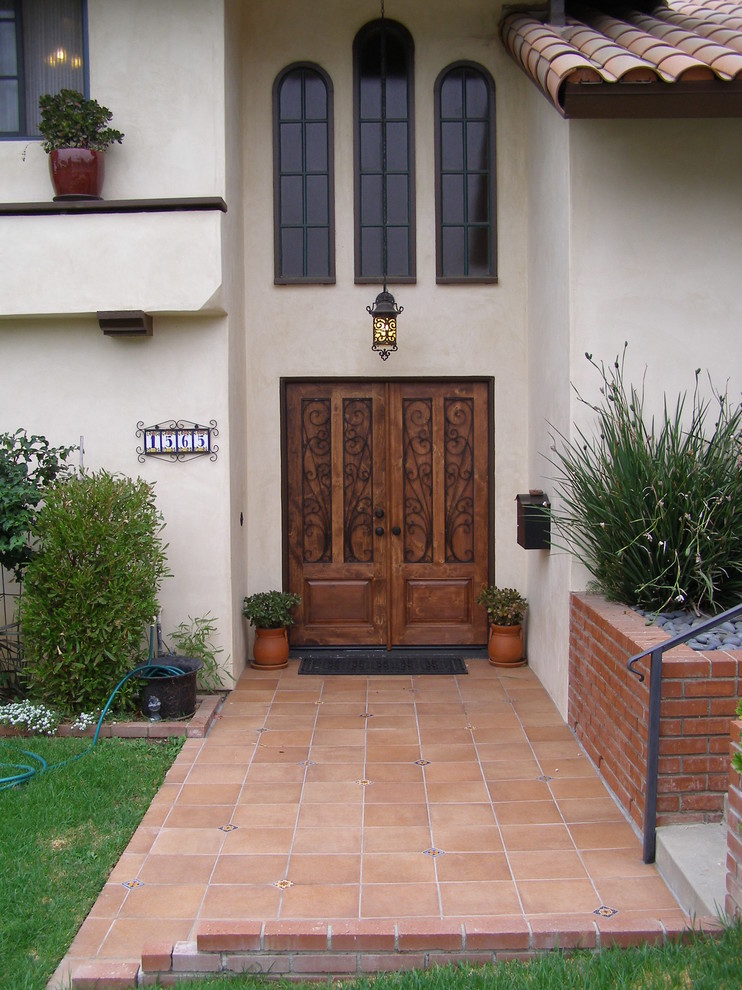 Пример оригинального дизайна: большое фойе в средиземноморском стиле с бежевыми стенами, полом из керамической плитки, двустворчатой входной дверью и входной дверью из темного дерева