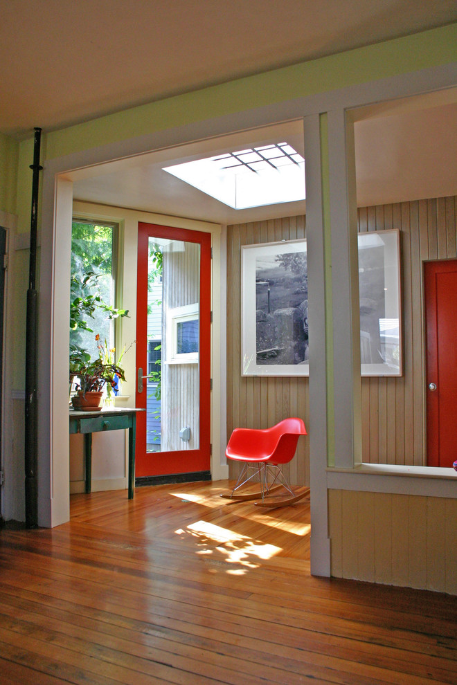 Diseño de distribuidor actual de tamaño medio con paredes beige, suelo de madera en tonos medios, puerta simple y puerta roja