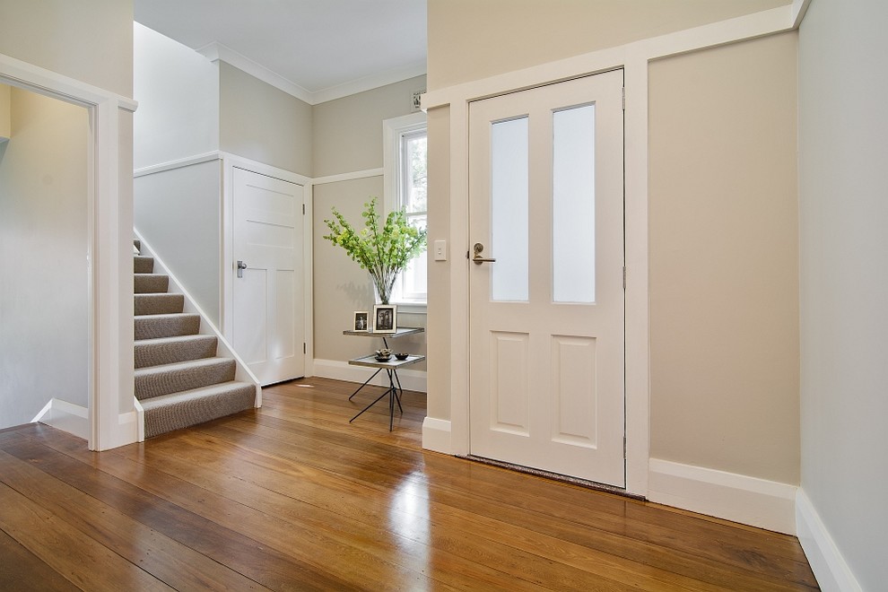 Foto di un corridoio classico di medie dimensioni con pareti beige, parquet chiaro, una porta singola, una porta bianca e pavimento marrone