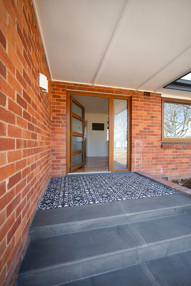 This is an example of a medium sized contemporary front door in Canberra - Queanbeyan with white walls, ceramic flooring, a single front door, a medium wood front door, blue floors and brick walls.