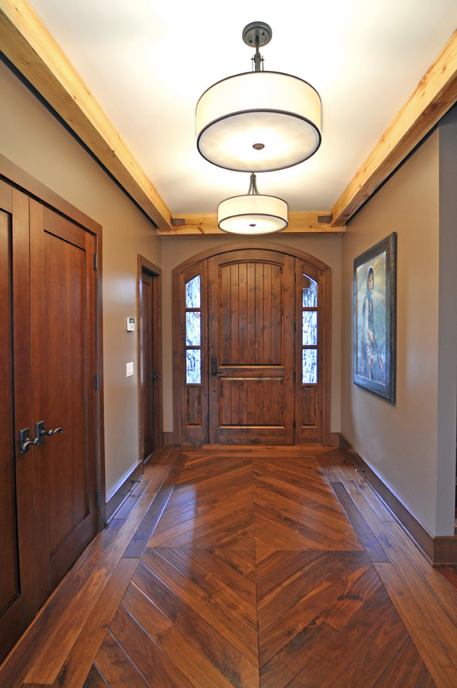 This is an example of a traditional front door in Calgary with brown walls, medium hardwood flooring, a single front door, a medium wood front door and feature lighting.