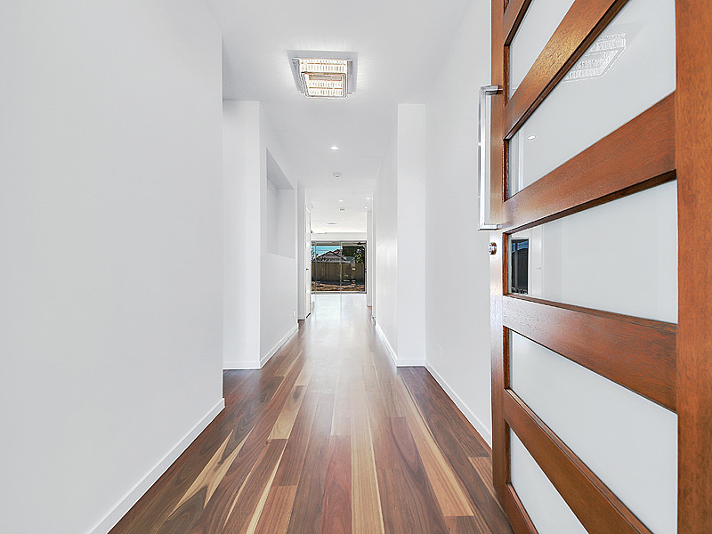 This is an example of a medium sized modern front door in Brisbane with white walls, medium hardwood flooring, a single front door, a medium wood front door and brown floors.