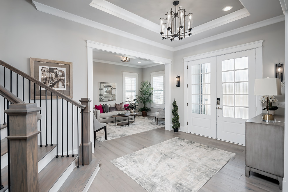 Mittelgroßes Foyer mit grauer Wandfarbe, hellem Holzboden, Doppeltür, weißer Haustür und eingelassener Decke in Charlotte