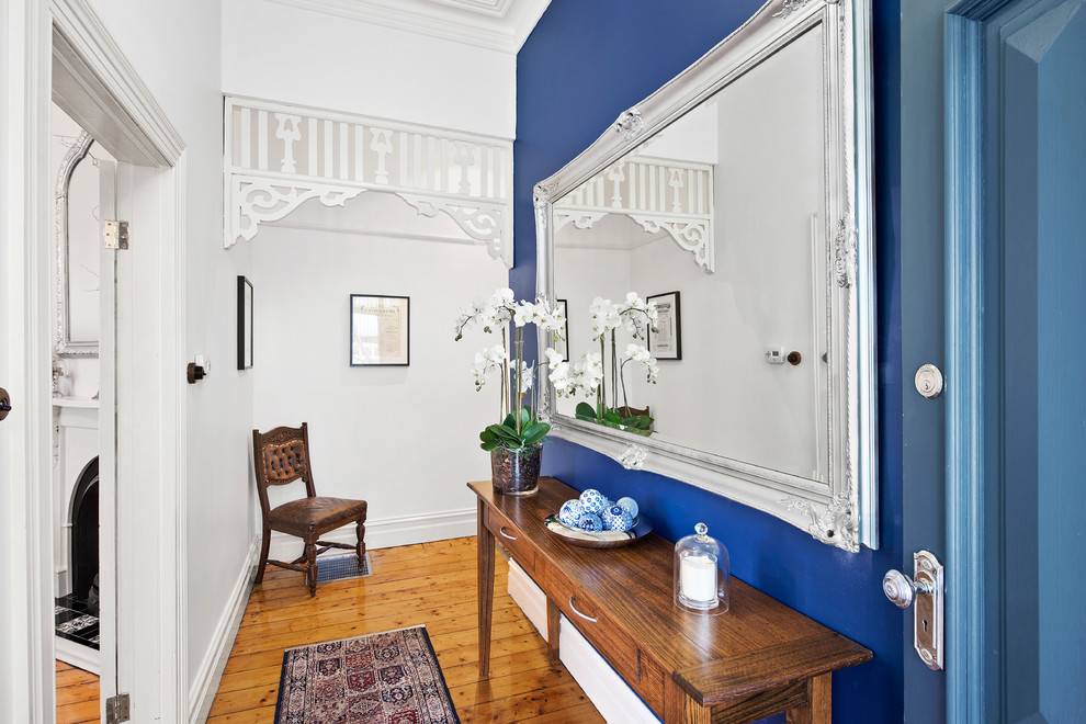 Источник вдохновения для домашнего уюта: узкая прихожая в классическом стиле с синими стенами, светлым паркетным полом, одностворчатой входной дверью и синей входной дверью
