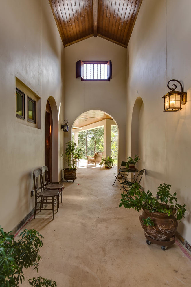 This is an example of a large mediterranean foyer in Austin with beige walls, concrete flooring, a double front door, a medium wood front door and beige floors.