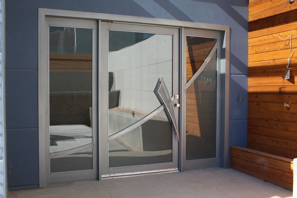 Пример оригинального дизайна: большая входная дверь в стиле модернизм с синими стенами, бетонным полом, поворотной входной дверью, металлической входной дверью и серым полом