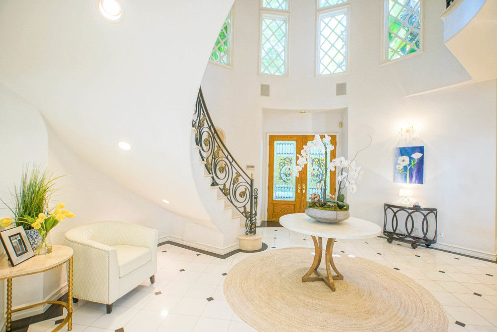 Inspiration pour un grand hall d'entrée traditionnel avec un mur blanc, un sol en marbre, une porte double et une porte en bois brun.