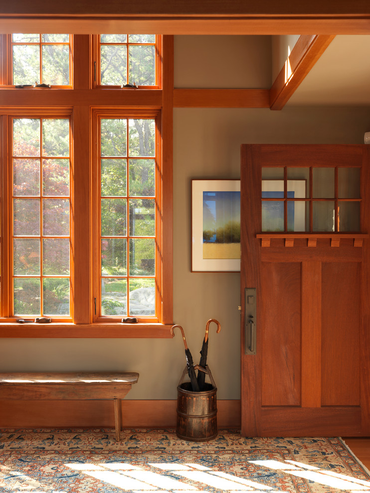 Modelo de distribuidor de estilo americano de tamaño medio con paredes grises, suelo de madera en tonos medios, puerta simple, puerta de madera en tonos medios y suelo marrón