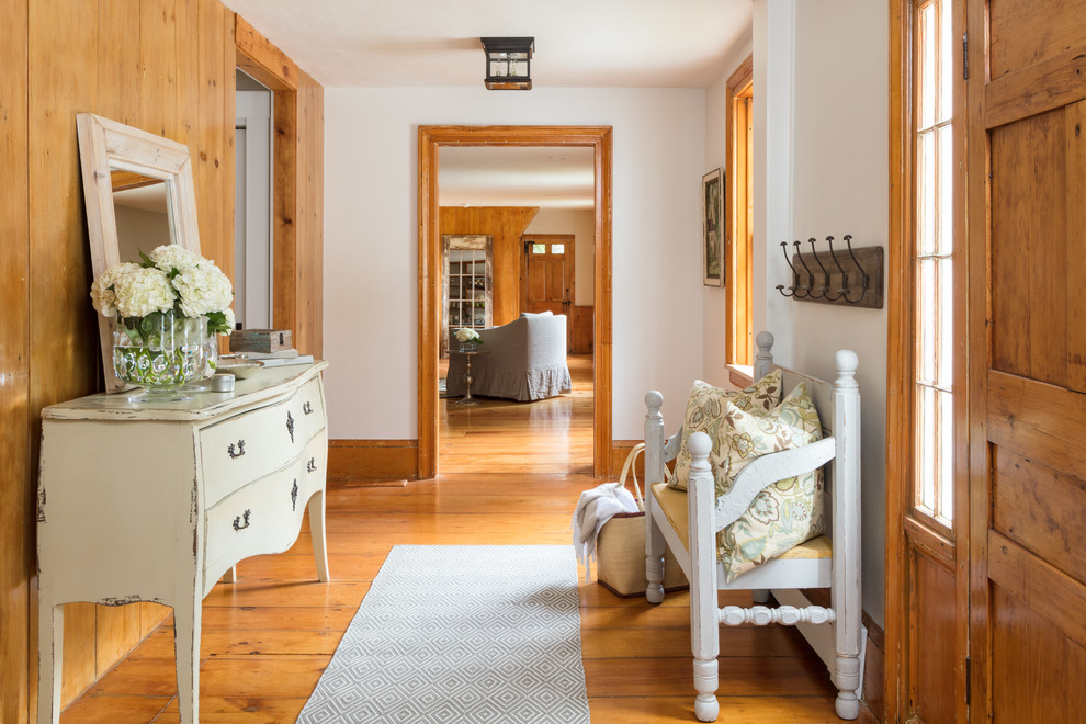 Immagine di una piccola porta d'ingresso country con pareti bianche, pavimento in legno massello medio, una porta singola, una porta in legno bruno e pavimento marrone