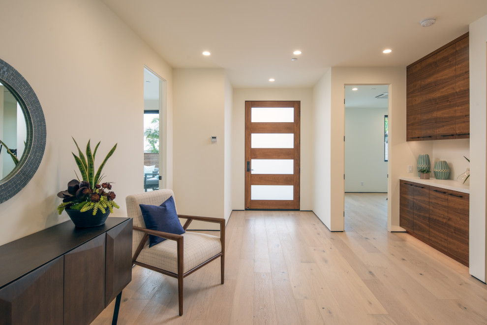 Inspiration pour un hall d'entrée minimaliste de taille moyenne avec un mur blanc, parquet clair, une porte simple, une porte en bois brun et un sol blanc.