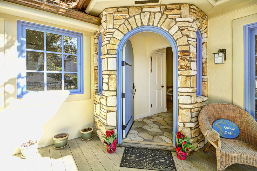 Imagen de puerta principal rural con puerta simple, puerta azul, paredes amarillas, suelo de pizarra y suelo multicolor